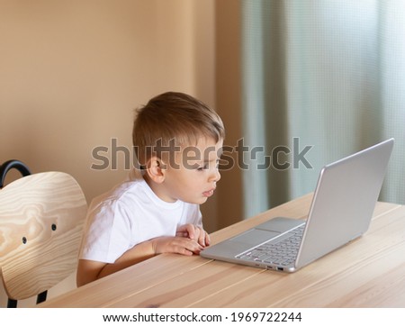 Little boy sitting at the laptop is is puzzled and thoughtful.