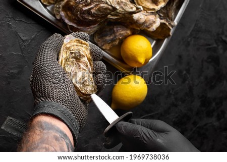 Selective focus at hand prepare fresh oysters on the countertop of seafood stall in market. Royalty-Free Stock Photo #1969738036