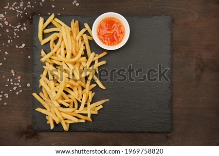 fast food fries and red hot sauce top view on a slate plate and himalayan salt horizontal photo