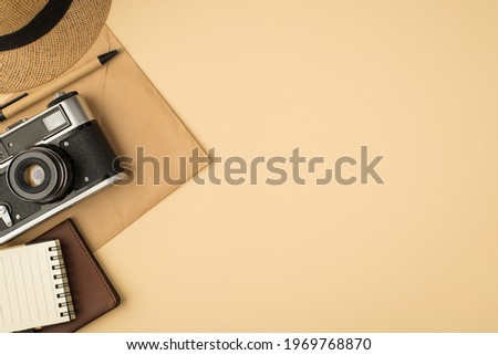 Top view photo of cap pen notebook passport cover and camera on craft paper envelope on isolated beige background with copyspace