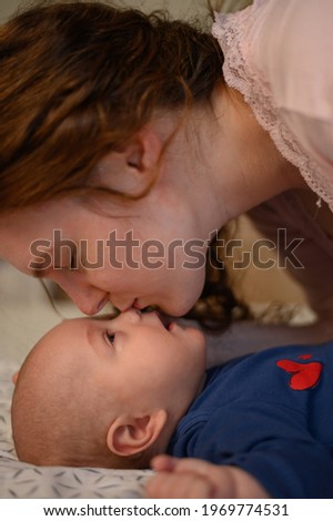 Mother bonding with her adorable baby boy while kissing him in his tiny nose