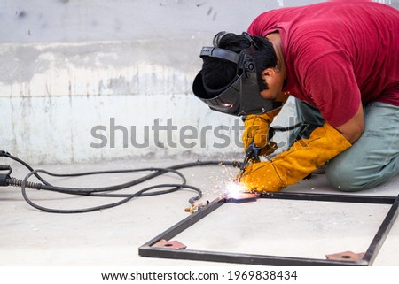 Male worker sparks arc welding with steel workpiece