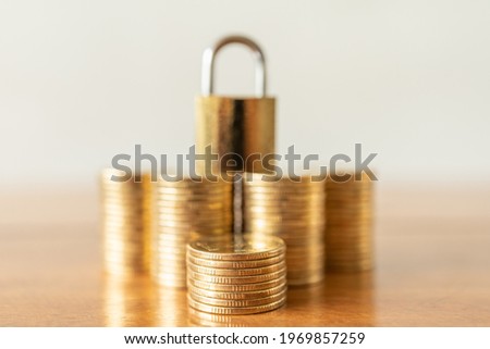 Money and Security Concept. Closeup of stack of gold coins with golden master key lock on top as background on wooden table.