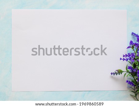 White sheet of paper on a blue background with a sprig of blue lavender. Place for your text. Advertising, invitation