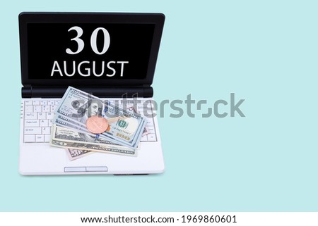 30th day of august. Laptop with the date of 30 august and cryptocurrency Bitcoin, dollars on a blue background. Buy or sell cryptocurrency. Stock market concept. Summer month, day of the year concept.