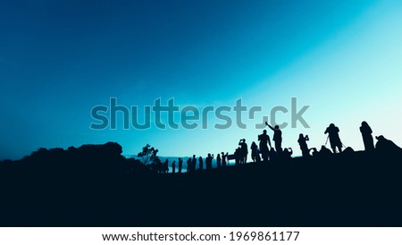 Silhouettes of tourist crowd waiting for the sunrise and doing activity, taking a photo, selfie with nature on the hill at viewpoint
