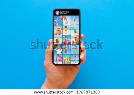 Someone's photo gallery on social media shown on the screen of mobile phone on blue background
