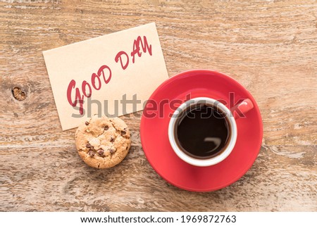 Coffee cup, chocolate cookie, note Good Day over wooden table. Coffee break concept.