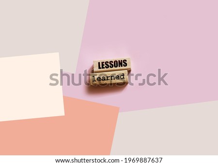 Wooden blocks wtih text Lessons learned on pink background. Business education concept.