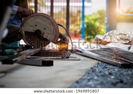 Labor men working with steel cutting machines. To cut steel for construction, home repair The steel was being cut by a steel cutter, sparks shot out. The workman's hand is on the cutting machine. 