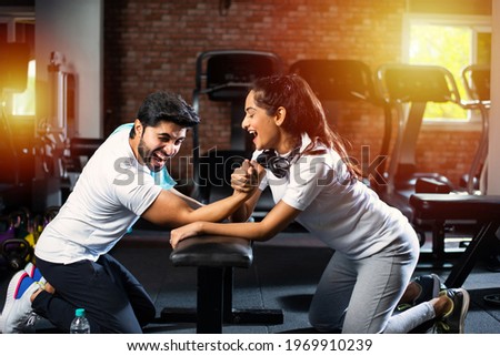 Arm wrestling challenge between a young Indian asian couple - having fun in the gym