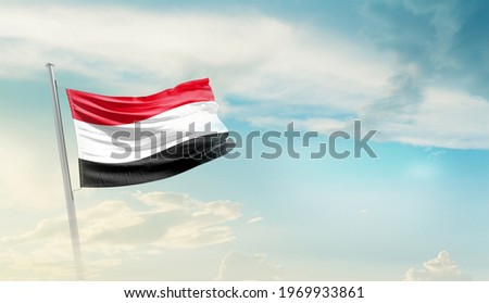 Yemen national flag waving in beautiful sky. Royalty-Free Stock Photo #1969933861