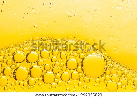 Beautiful and fantastic macro photo of water droplets in oil with a yellow background. Abstract art 