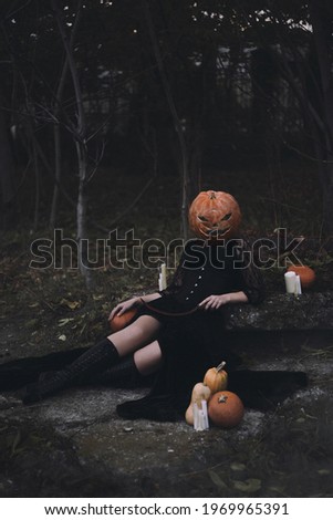 Girl in black halloween costume with a pumpkin instead of a head
