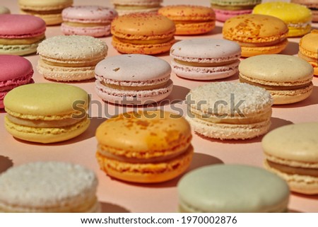 Colorful French macarons on light pink surface