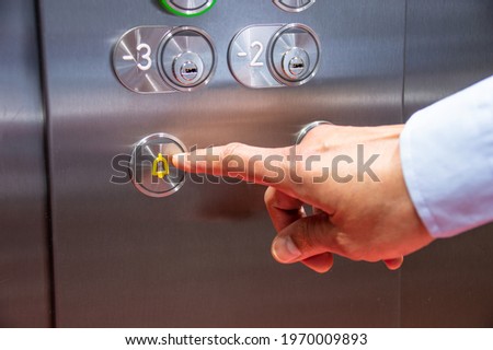 Close-up of hand pressing the alarm button in the elevator