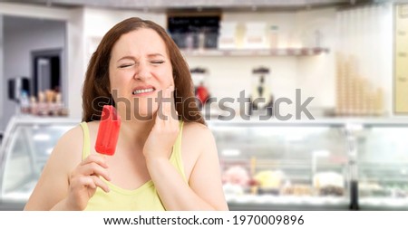 Portrait of a woman with hypersensitivity biting an ice cream in an ice cream parlor 
 Royalty-Free Stock Photo #1970009896