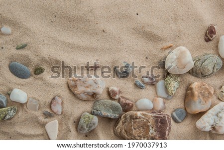 multicolored river pebbles stones randomly lie on the sand next to the sea. Macro photography. Close-up background concept, copy space.