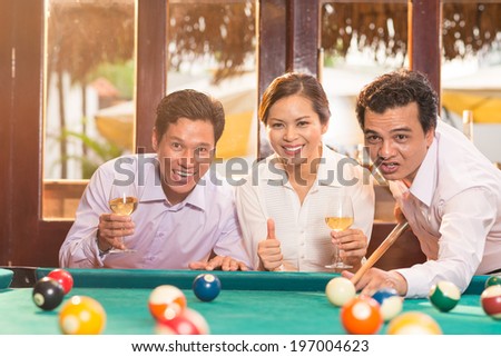 Friends cheering a man while he is hitting the billiard ball