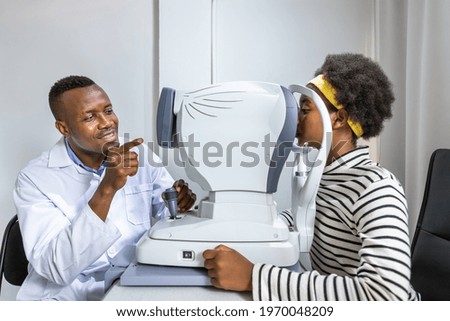 African young woman girl doing eye test checking examination using autorefractor in clinic or optical shop. Eyecare concept. Royalty-Free Stock Photo #1970048209