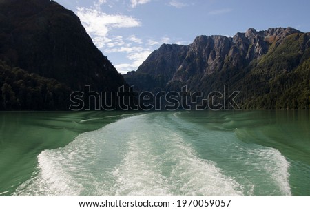 cold lake with its green waters near Bariloche, wake of water from catamaran and view of the mountains