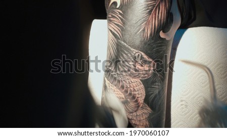 Close up photo of doing black tattoo of snake in studio