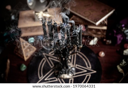 A fortune teller, witch stuff on a table, candles and fortune-telling objects. The concept of divination, astrology and esotericism Royalty-Free Stock Photo #1970064331