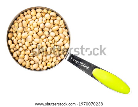 top view of dried soybeans in measuring cup cutout on white background
