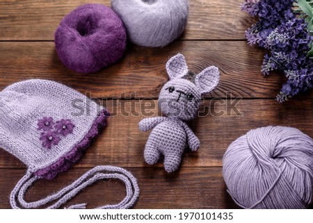 Toy hare tied from woolen threads on a dark background. Manual work, hobby