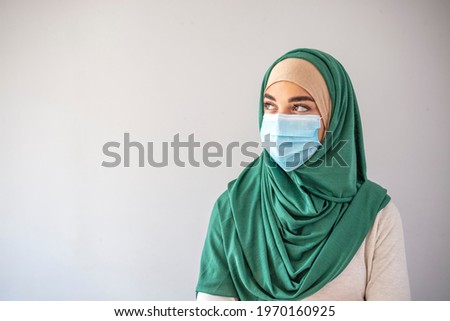 Muslim girl wearing surgical mask for protection. Hijab woman take a mask. Beautiful Arab young woman with disposable face mask. Protection versus viruses and infection.