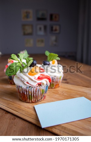 three cupcakes on a wooden background with business cards for your design