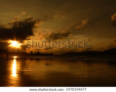 Yellow sunrise at the beach, with reflection in the water.