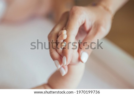 Close-up photo of a newborn baby holding her mother's finger, a woman and a baby