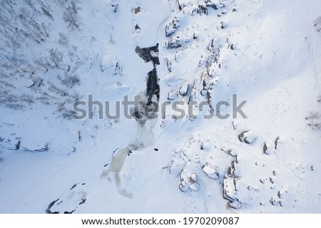 Flying above frozen forest and winding river in winter.