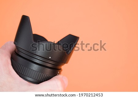 A closeup shot of a hand holding a black camera on a colorful background