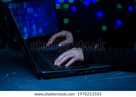 A female computer programmer or hacker prints a code on a laptop keyboard to break into a secret organization system.