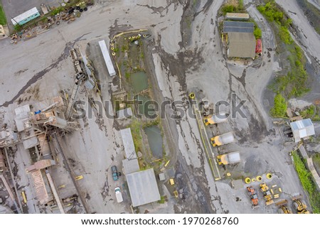 Aerial view from above of open cast mining quarry with machinery at work