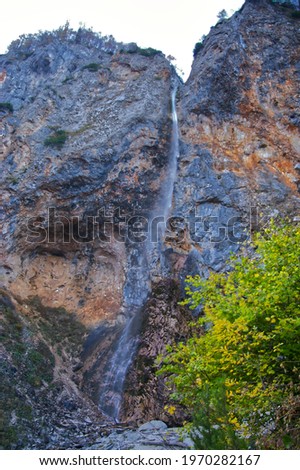 A vertical shot of the Rinka Falls in the Logar Valley in Slovenia with bright trees around