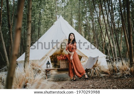 A beautiful woman dressed in a brown dress in the middle of a forest rich in colorful flowers, beautiful during daytime, touring the flower garden and taking pictures for relaxing and happy vacation.