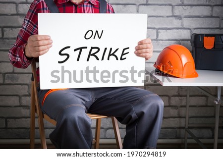 Worker on strike, builder holding poster with written protest message. Royalty-Free Stock Photo #1970294819