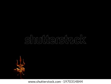 A golden metal statue on a dark black background with a copy space