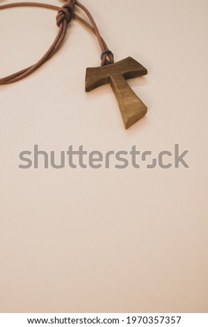 A closeup shot of a wooden tau cross necklace isolated on a white background