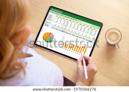 Woman working with spreadsheet document on tablet computer Royalty-Free Stock Photo #1970366276