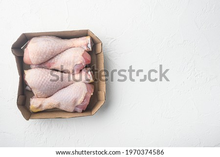 Fresh chicken leg set, in paper Pack, on white stone background, top view flat lay, with copy space for text