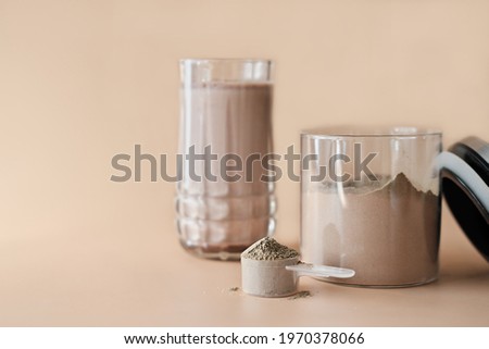scoop of collagen peptides powder with chocolate flavor in a jar and protein shake in a glass. supplement for healty living and muscle training.  Royalty-Free Stock Photo #1970378066