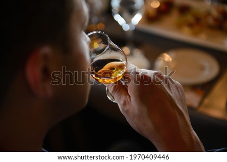 Man tasting cognac holding glass close to nose smelling the aroma Royalty-Free Stock Photo #1970409446