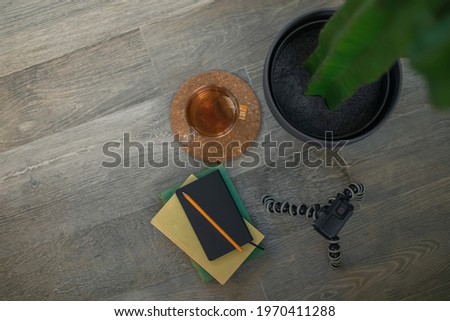 Top view on the wooden floor with books, notebook, action cam and cup of tea. Cozy, relaxing and peaceful atmosphere. Recording equipment and shooting video. Home working, content creators concept.