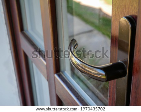 Plastic door handle close up shot on brown PVC door at a residential house. Royalty-Free Stock Photo #1970435702