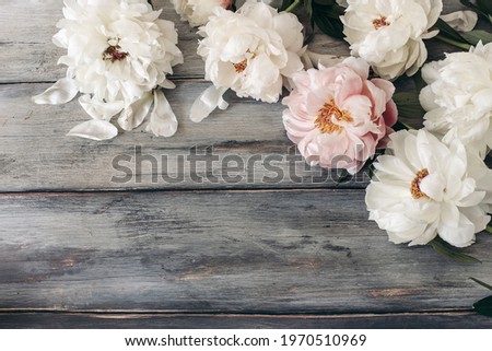 Decorative floral frame, banner made of pink and white peonies flowers. Old grey wooden table background. Empty copy space. Flat lay, top view. Picture for blog. Summer wedding or birthday concept.