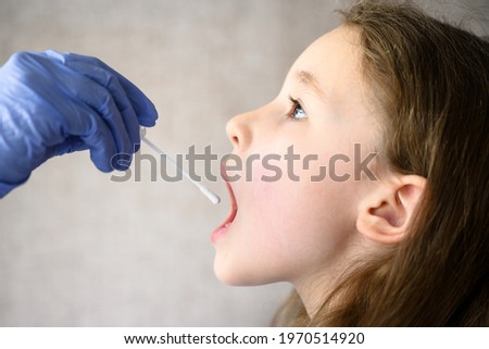 PCR test of child for COVID-19 or monkey pox, doctor holds swab for saliva sample of kid. Little girl opens mouth, face close-up. Concept of corona virus, antigen, children's health and school. Royalty-Free Stock Photo #1970514920